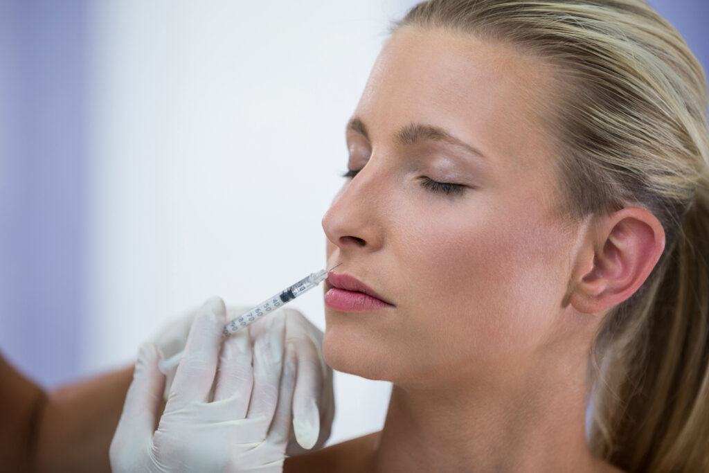 Aplicación de toxina botulínica en el rostro de una mujer