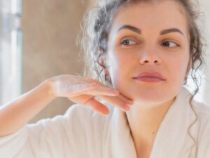 Mujer con la piel revitalizada tocándose el rostro