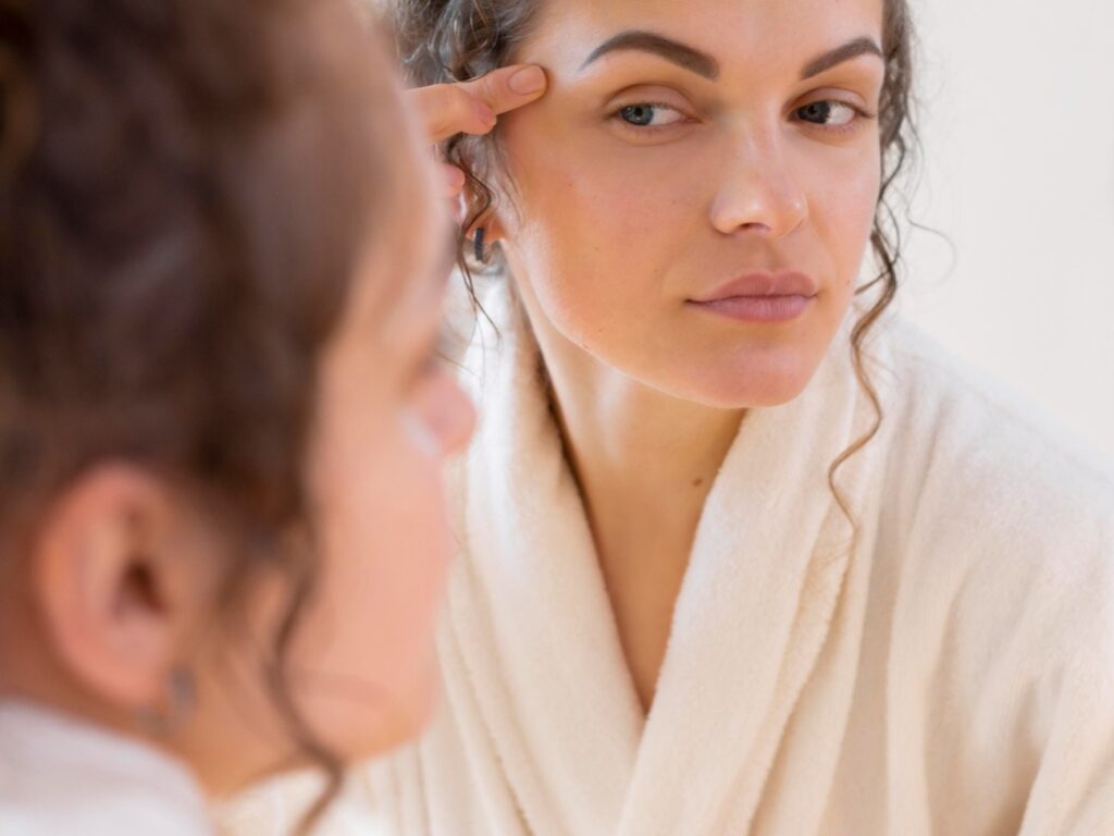 Mujer observando su rostro frente al espejo
